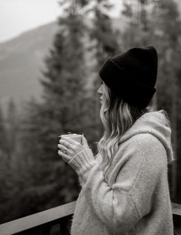 A woman in deep solace drinking coffee and looking out at the mountains 