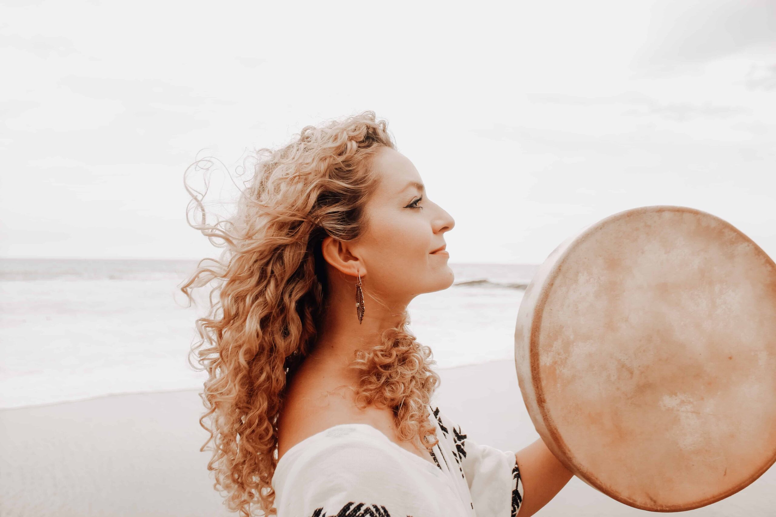 Woman beating a drum at the beach to discover the root causes of a problem