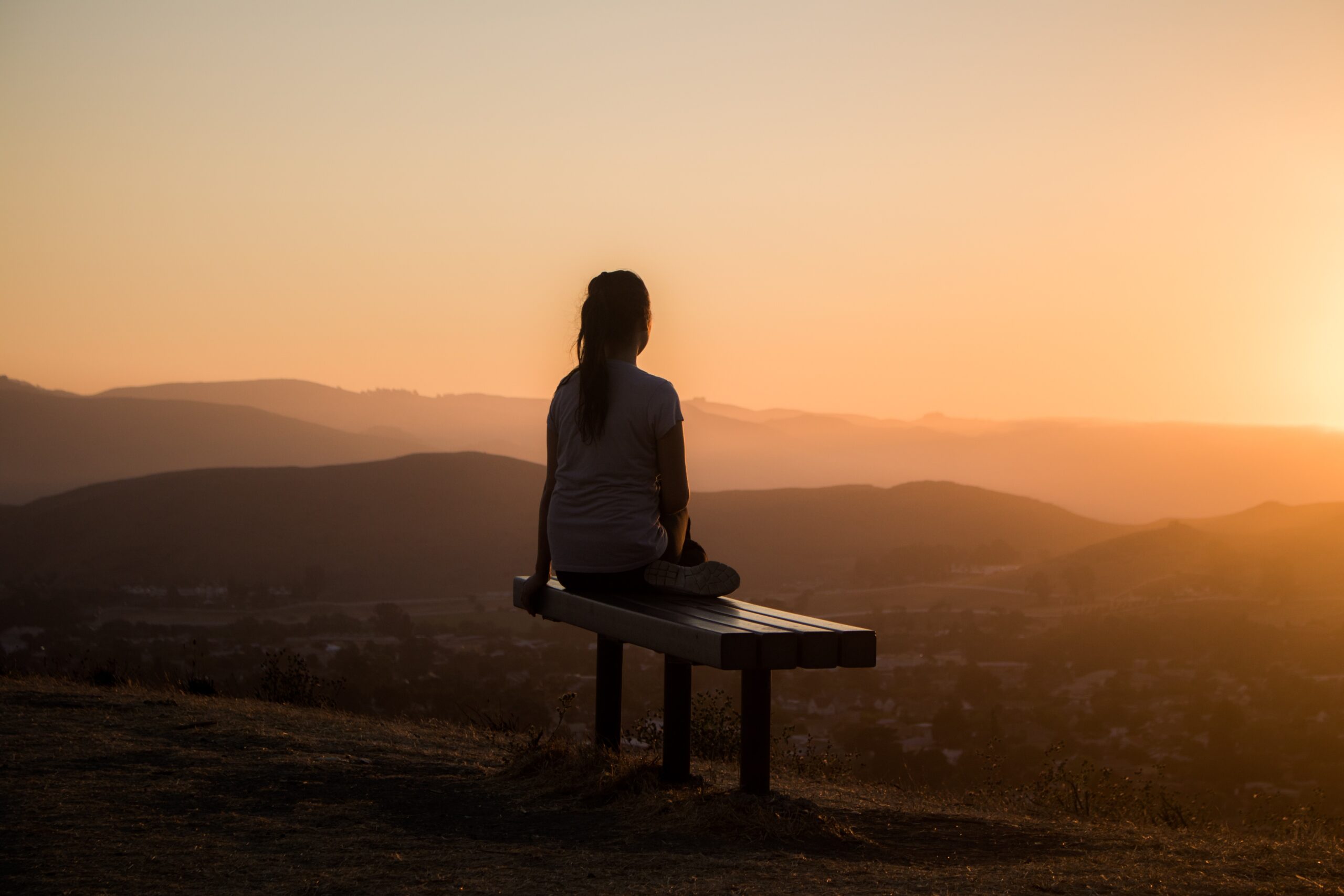 Woman sitting on a bench overlooking mountains