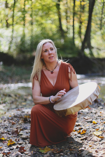 Depth hypnosis practitioner kneeling in a forest and beating on a drum
